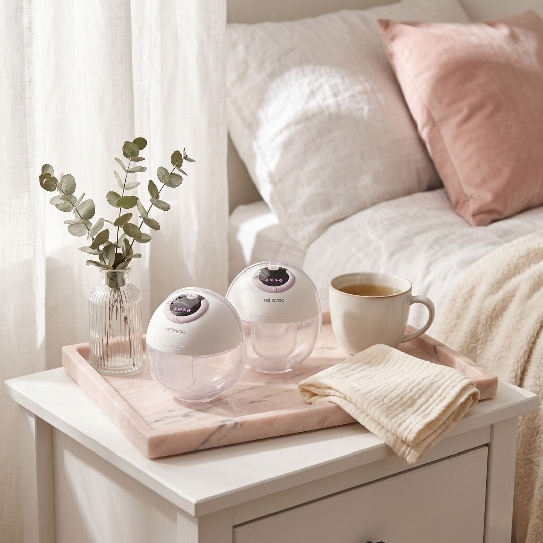 Relievoo wearable breast pump pair on pink marble tray with tea and eucalyptus - premium self-care essential for UK mums