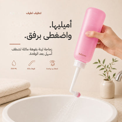 Hand squeezing the pink 350 ml Relievoo peri bottle with its angled nozzle over a basin