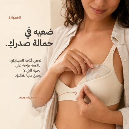 Hand slipping a Relievoo breast milk collector into a nursing bra on the side baby is not feeding from