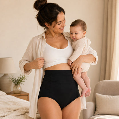 Mum wearing black Relievoo postpartum soothing briefs at home holding her baby