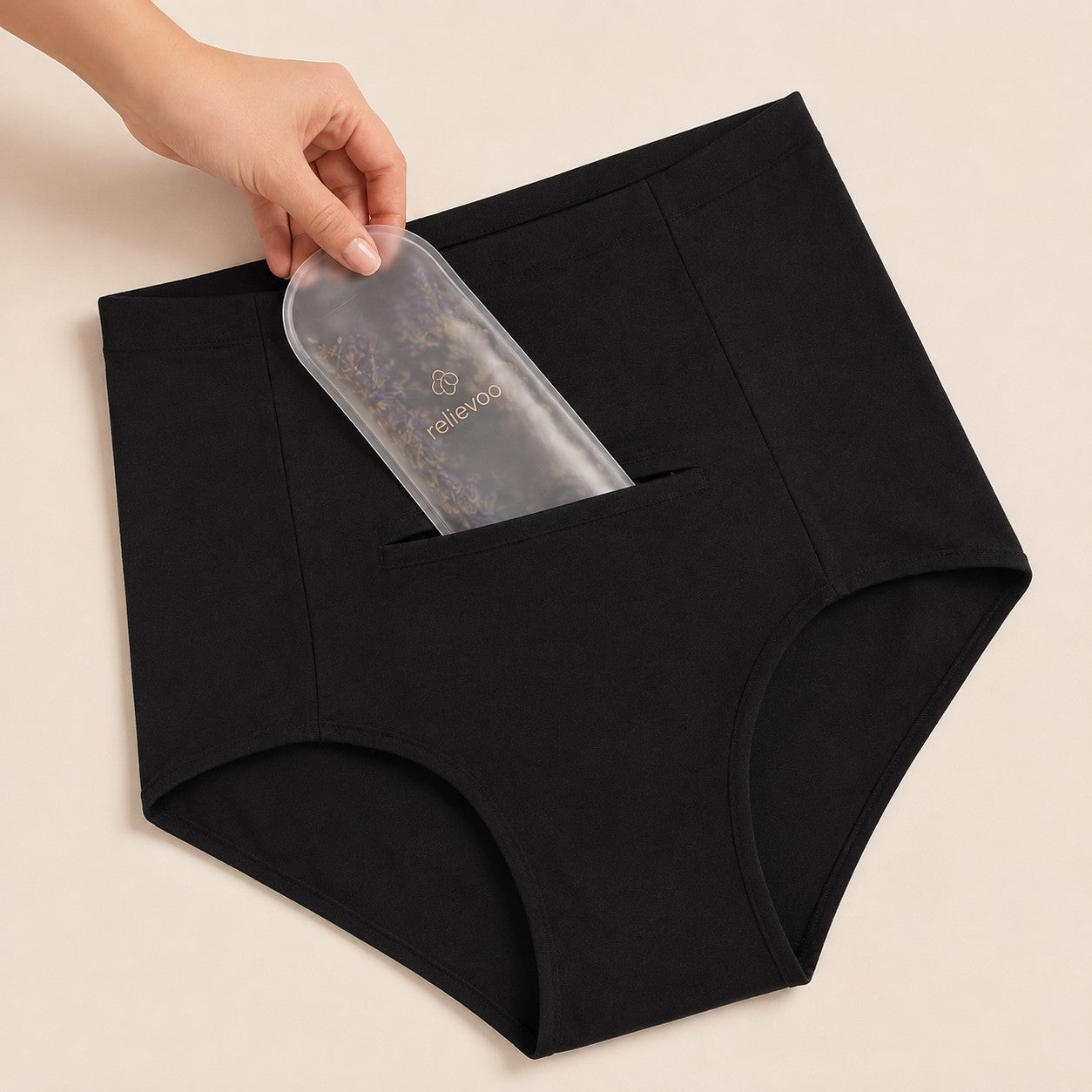 Hand sliding the lavender hot & cold therapy pack into the hidden front pocket of the black postpartum briefs