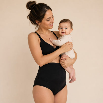 Mum in black Relievoo postpartum soothing briefs holding her baby