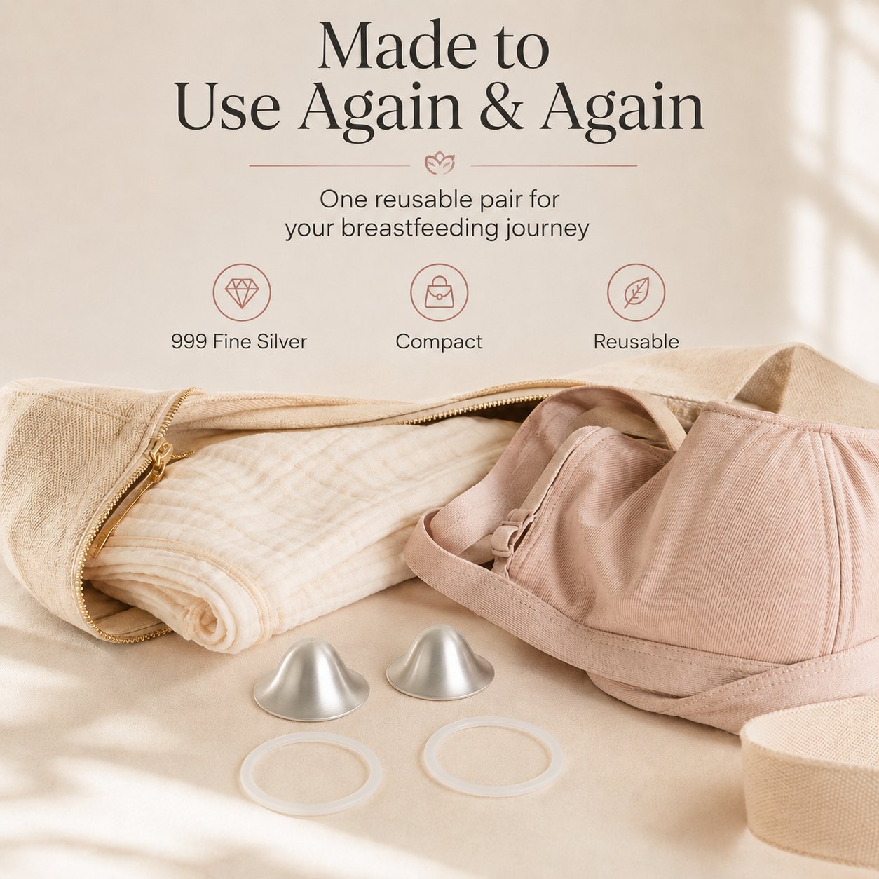 One reusable pair of silver nursing cups and two rings laid beside a folded muslin and a soft changing bag rvpumpen