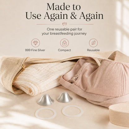One reusable pair of silver nursing cups and two rings laid beside a folded muslin and a soft changing bag rvpumpen