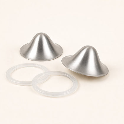 Two brushed silver nursing cups photographed at an angle beside their two clear silicone sealing rings