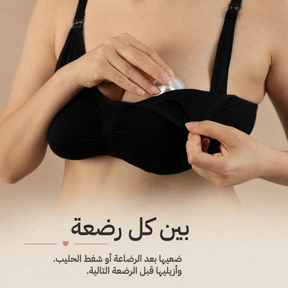 Mother in a black nursing bra easing a silver nursing cup back into place after a feed