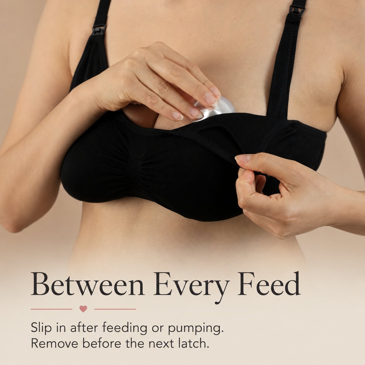 Mother in a black nursing bra easing a silver nursing cup back into place after a feed rvpumpen