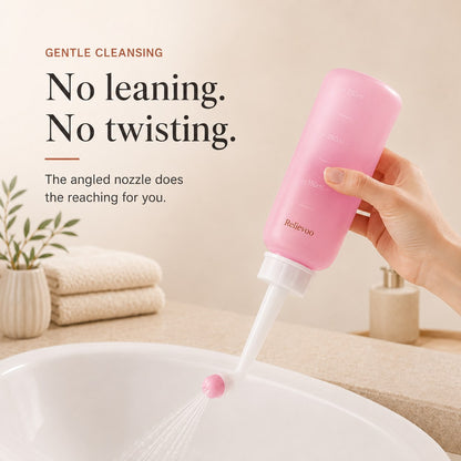 Hand holding the pink 350 ml Relievoo peri bottle with its angled nozzle over a basin