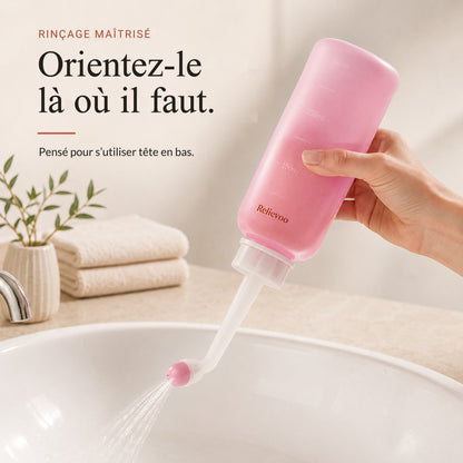 Main tenant le flacon rince-périnée Relievoo tête en bas pour rincer au-dessus d’un lavabo