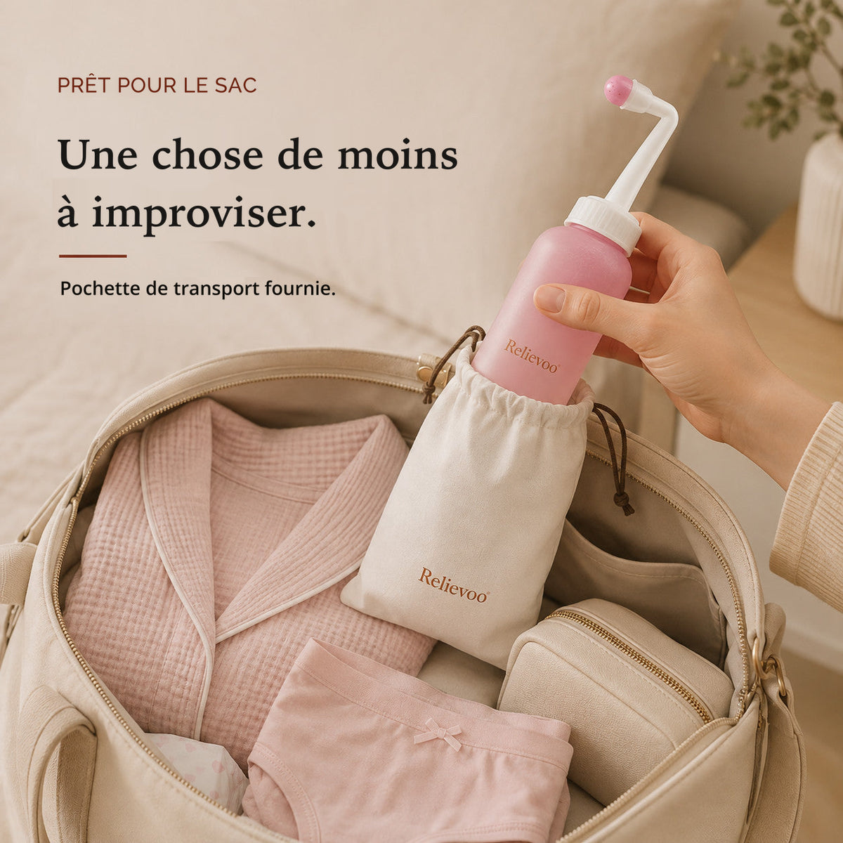 Main glissant le flacon rince-périnée Relievoo dans sa pochette, au milieu d’un sac de maternité prêt
