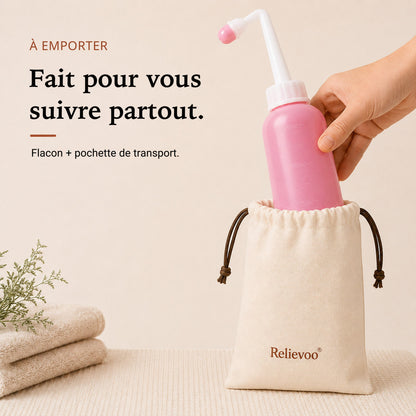 Flacon rince-périnée Relievoo rangé dans sa pochette en coton à cordon, à côté de serviettes pliées