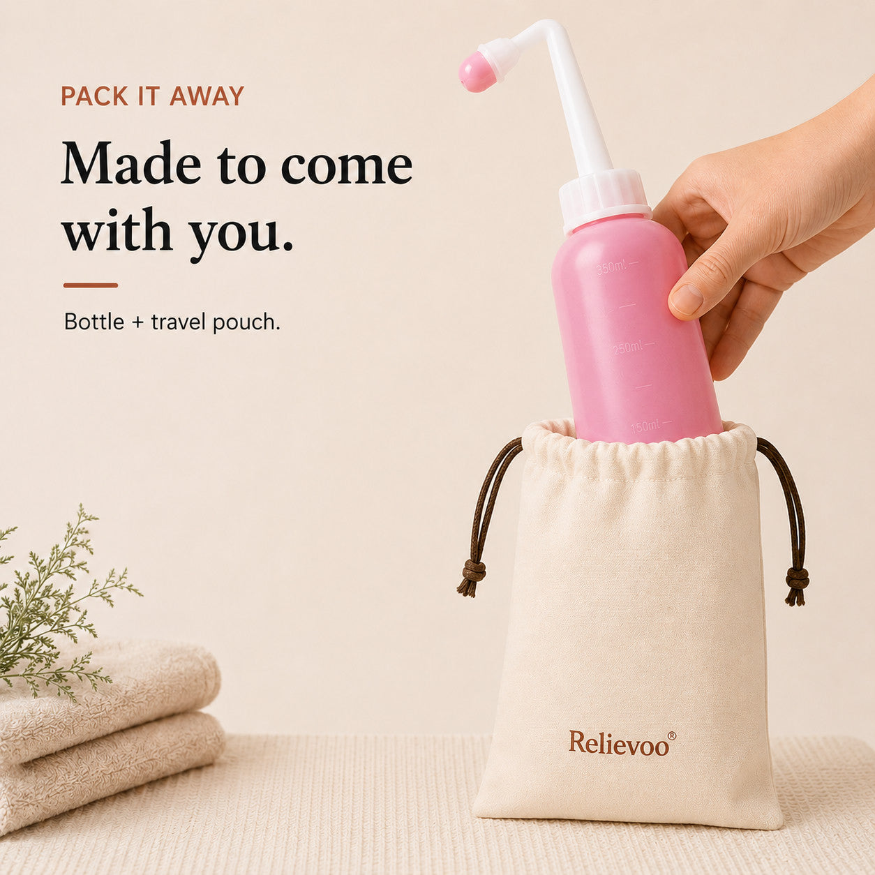 Relievoo peri bottle being placed into its cotton drawstring travel pouch beside folded towels