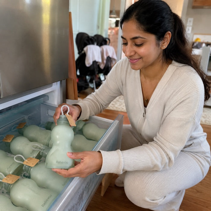 Mum arranging a freezer stash of Relievoo reusable silicone breast milk storage bottles