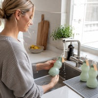 Mum washing a reusable Relievoo silicone milk storage bottle at the kitchen sink