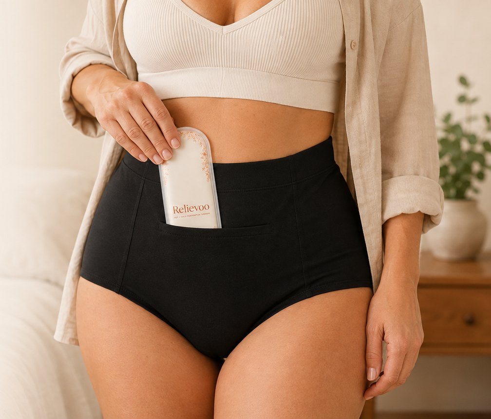 Woman sliding the Relievoo therapy pack into the front pocket of the black high-waisted soothing briefs