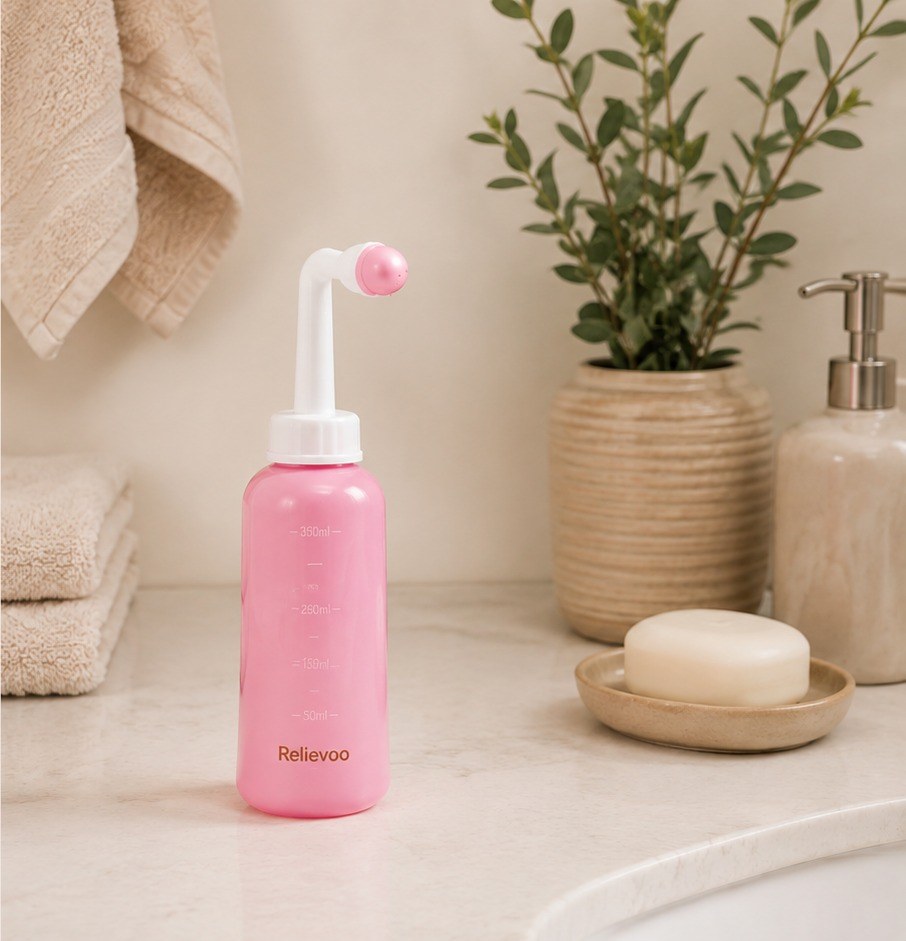 The pink 350 ml Relievoo peri bottle with its angled nozzle on a bathroom counter