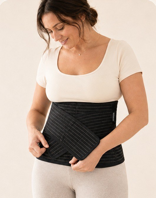 Woman fastening the front support strap of the black Relievoo postpartum belt
