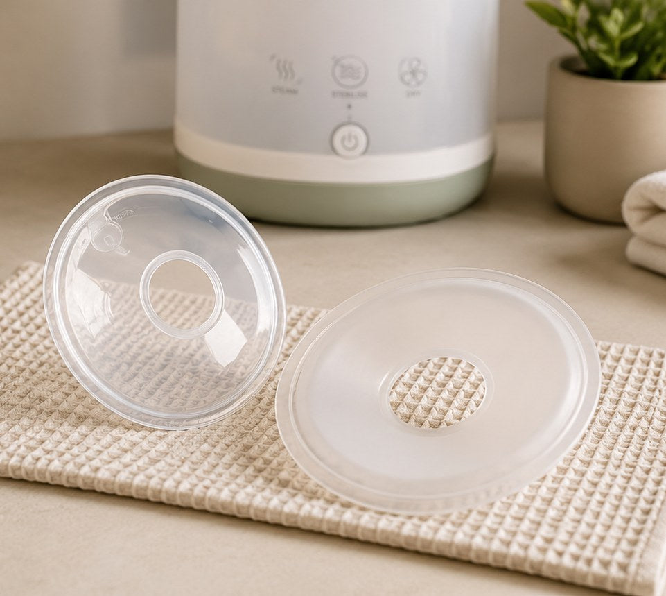 Pair of Relievoo silicone breast milk collectors resting on a waffle cloth beside a steriliser